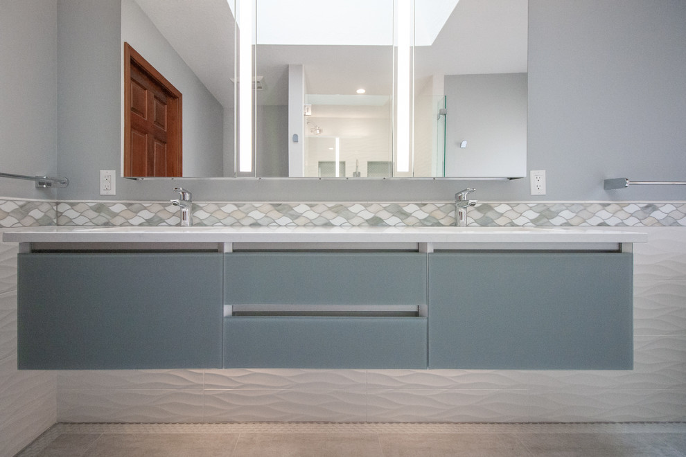 Foto di una stanza da bagno padronale moderna di medie dimensioni con ante blu, vasca freestanding, doccia alcova, piastrelle bianche, lavabo sottopiano, pavimento grigio e porta doccia a battente