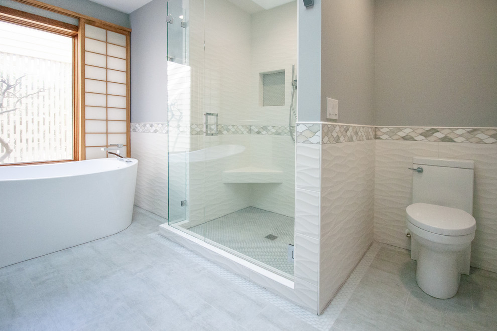 Идея дизайна: главная ванная комната среднего размера в стиле модернизм с синими фасадами, отдельно стоящей ванной, душем в нише, белой плиткой, врезной раковиной, серым полом и душем с распашными дверями