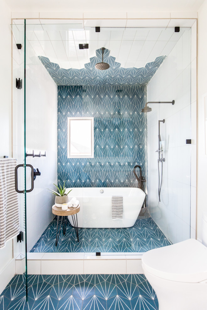 На фото: ванная комната в современном стиле с отдельно стоящей ванной, душевой комнатой, синей плиткой, белой плиткой, белыми стенами, синим полом и душем с распашными дверями