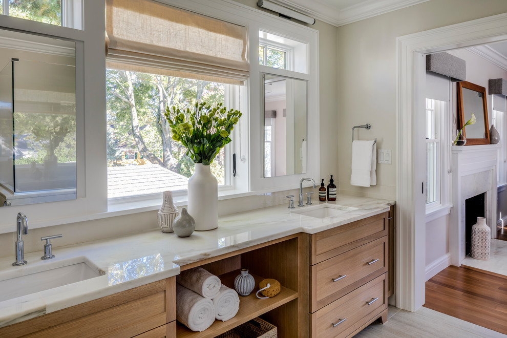 Photo of a medium sized traditional ensuite bathroom in Boston with recessed-panel cabinets, medium wood cabinets, a corner shower, a one-piece toilet, beige walls, ceramic flooring, a console sink, marble worktops, multi-coloured floors and a hinged door.
