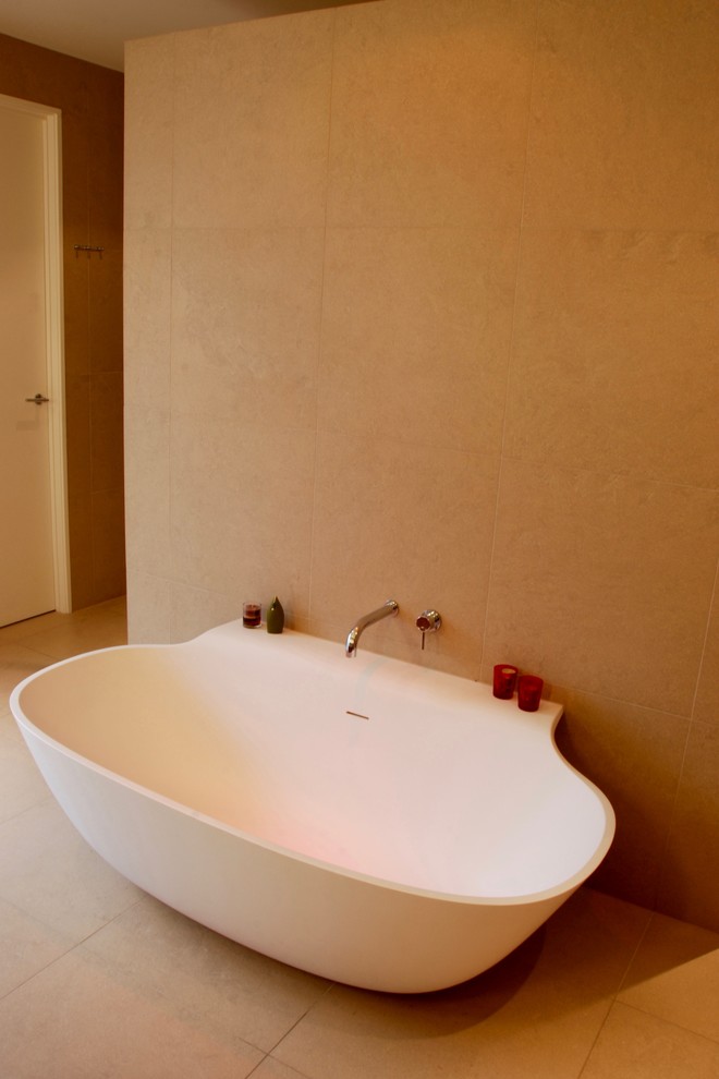 Réalisation d'une salle de bain design avec une baignoire indépendante, un carrelage beige, un mur beige et un sol beige.