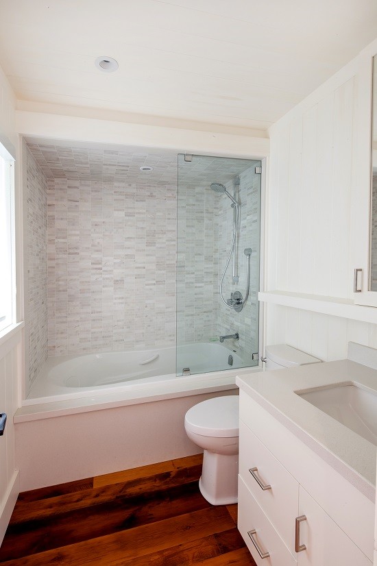 Ispirazione per una stanza da bagno con doccia minimalista di medie dimensioni con vasca/doccia, WC sospeso, piastrelle bianche, pareti bianche, lavabo da incasso e pavimento marrone