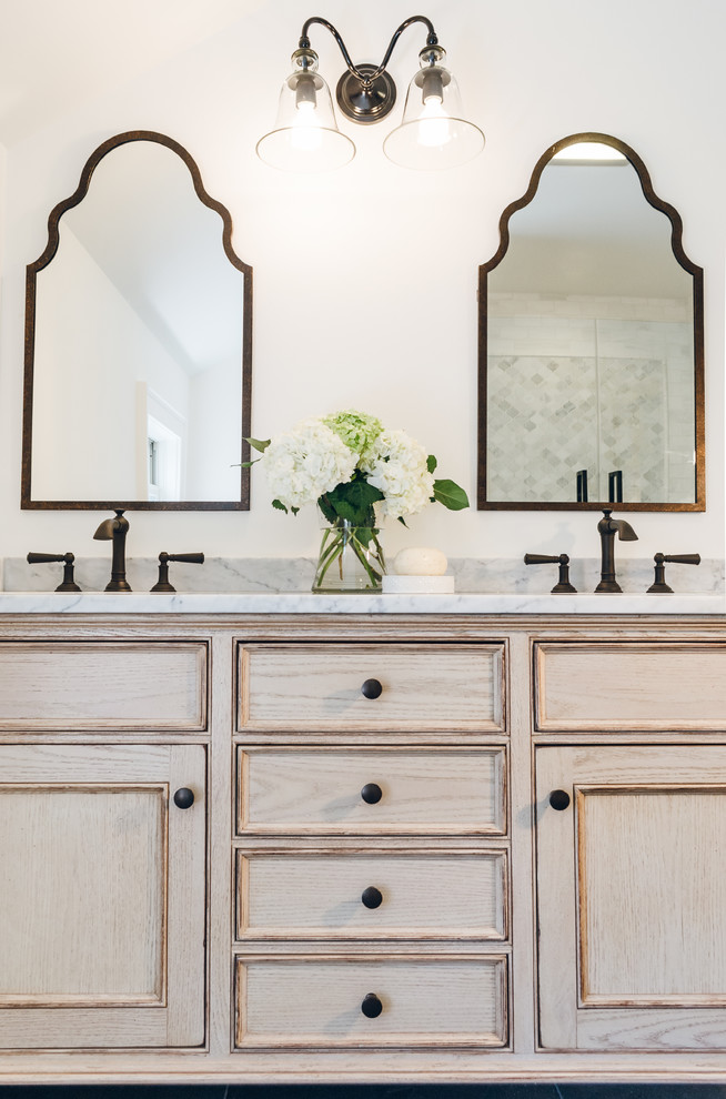Exempel på ett mellanstort klassiskt en-suite badrum, med luckor med profilerade fronter, skåp i slitet trä, ett badkar i en alkov, en dusch/badkar-kombination, en toalettstol med hel cisternkåpa, vit kakel, stenkakel, vita väggar, ett undermonterad handfat och marmorbänkskiva