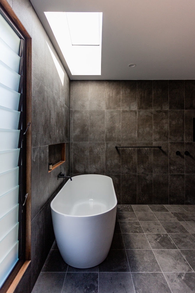 Ejemplo de cuarto de baño urbano de tamaño medio con bañera exenta, paredes negras, suelo de baldosas de cerámica y suelo negro