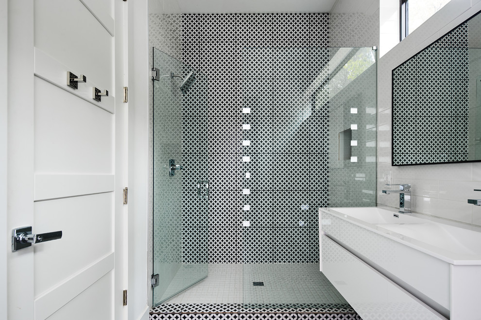 Идея дизайна: ванная комната среднего размера в стиле модернизм с плоскими фасадами, белыми фасадами, душем в нише, унитазом-моноблоком, черно-белой плиткой, плиткой мозаикой, белыми стенами, полом из мозаичной плитки, душевой кабиной, монолитной раковиной, столешницей из искусственного кварца, душем с распашными дверями и белой столешницей