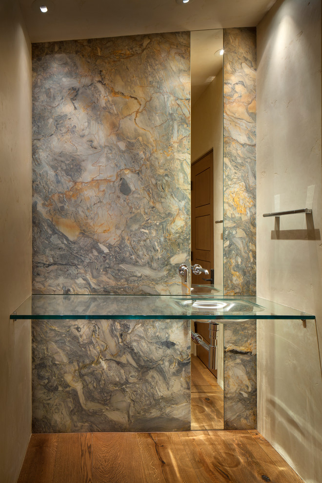 Ejemplo de cuarto de baño actual de tamaño medio con lavabo encastrado, encimera de vidrio, paredes beige y suelo de madera en tonos medios