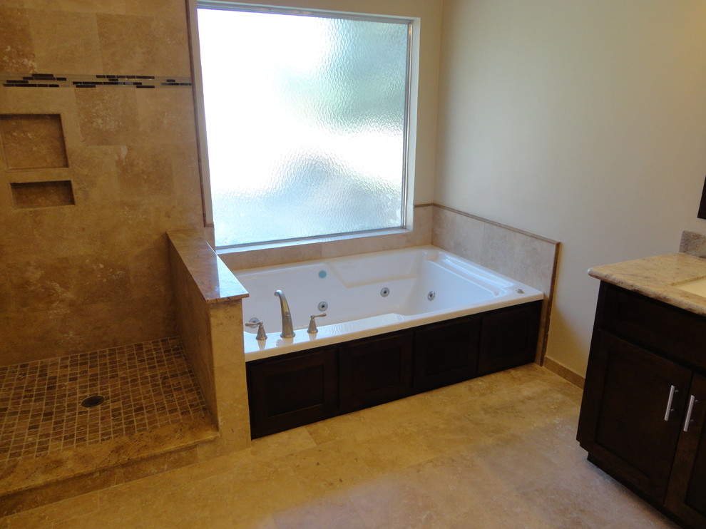 Example of a large trendy master beige tile and stone tile travertine floor walk-in shower design in Houston with a vessel sink, shaker cabinets, brown cabinets, granite countertops, a hot tub, a two-piece toilet and beige walls