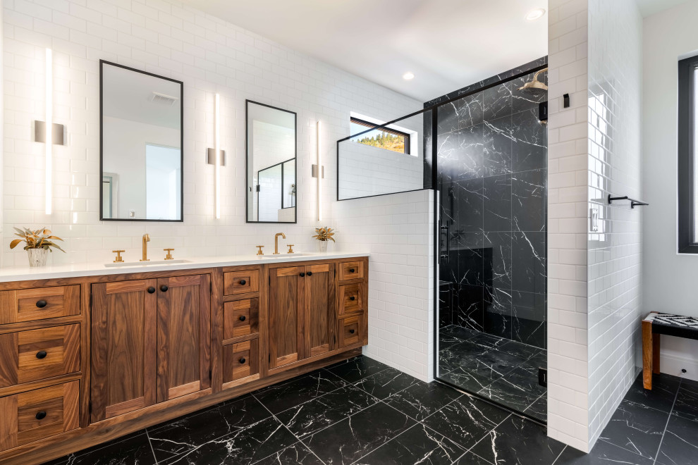 Idée de décoration pour une douche en alcôve principale design en bois brun avec un placard à porte shaker, un carrelage noir, un mur blanc, un sol noir, une cabine de douche à porte battante, un plan de toilette blanc, meuble double vasque et meuble-lavabo encastré.