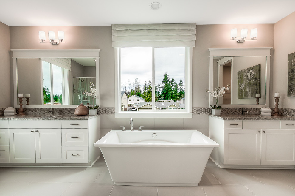 Photo of a classic ensuite bathroom in Seattle with shaker cabinets, white cabinets, a freestanding bath, a corner shower, grey tiles, ceramic tiles, grey walls, ceramic flooring and a submerged sink.