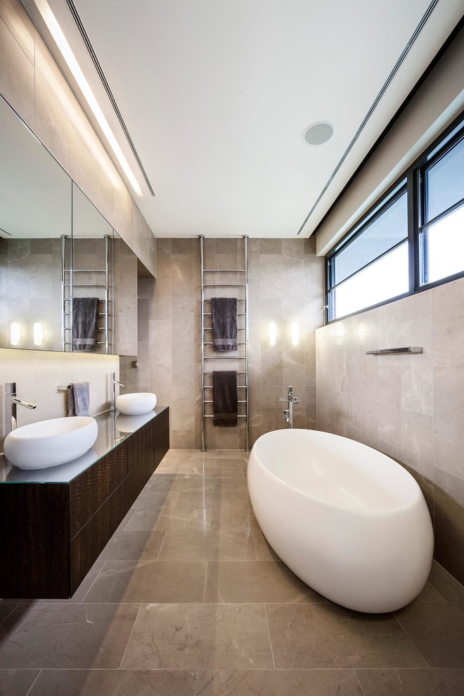 Foto på ett funkis badrum, med ett fristående handfat, ett fristående badkar, grå kakel och grå väggar