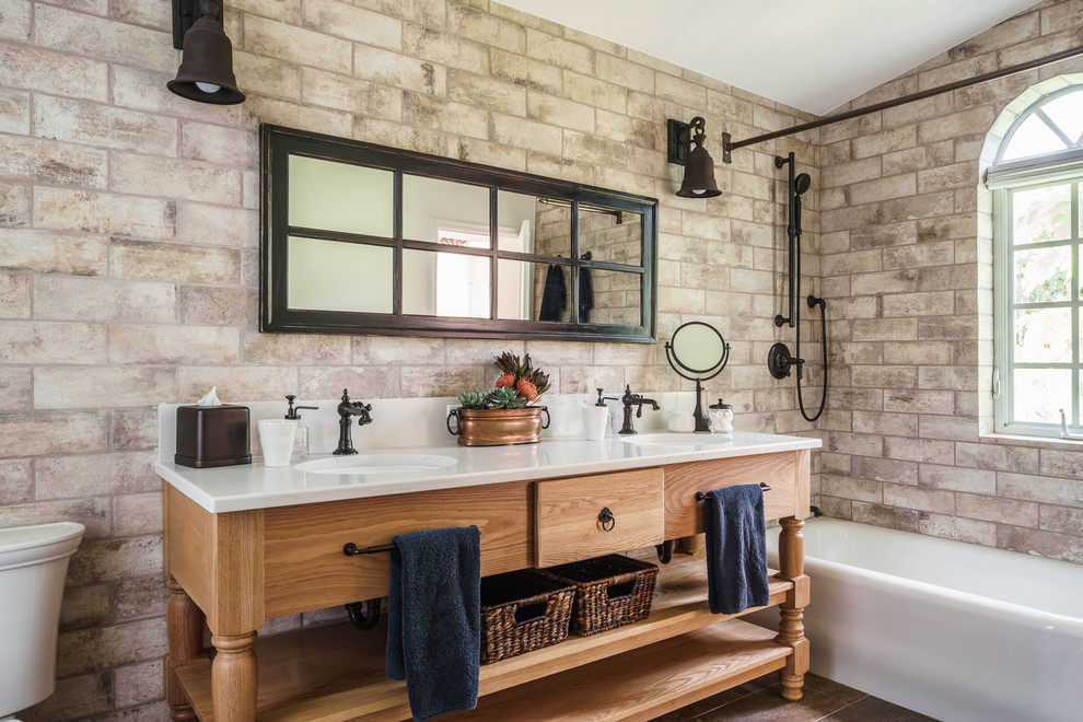 Modelo de cuarto de baño principal mediterráneo con puertas de armario de madera clara, combinación de ducha y bañera, lavabo bajoencimera y armarios con paneles lisos