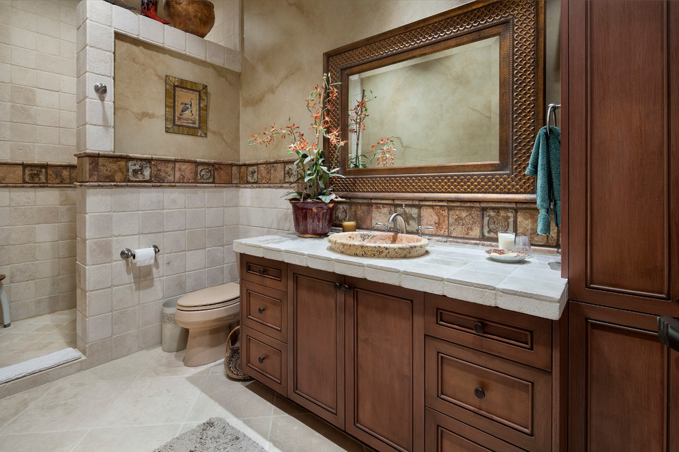 Ejemplo de cuarto de baño mediterráneo con lavabo encastrado, armarios con paneles empotrados, puertas de armario de madera en tonos medios, encimera de azulejos, ducha abierta, baldosas y/o azulejos beige y paredes beige