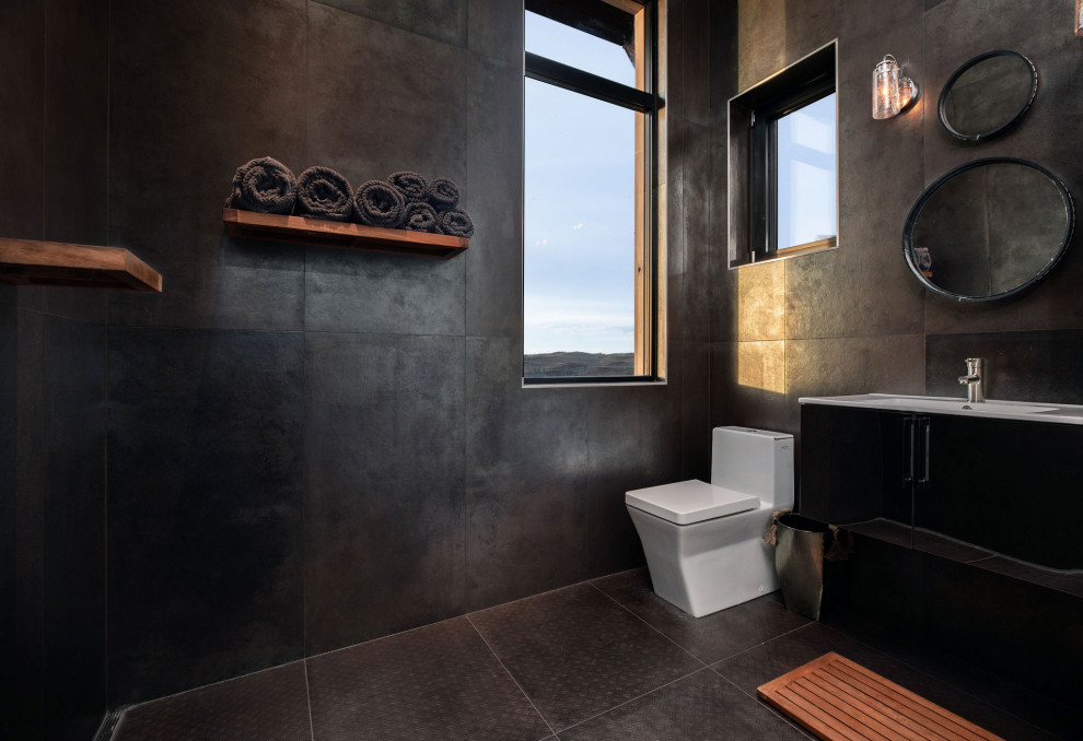 Modern inredning av ett mellanstort vit vitt badrum, med släta luckor, svarta skåp, en toalettstol med hel cisternkåpa, svart kakel, ett integrerad handfat, svart golv, grå väggar, granitbänkskiva, en öppen dusch, med dusch som är öppen och stenhäll