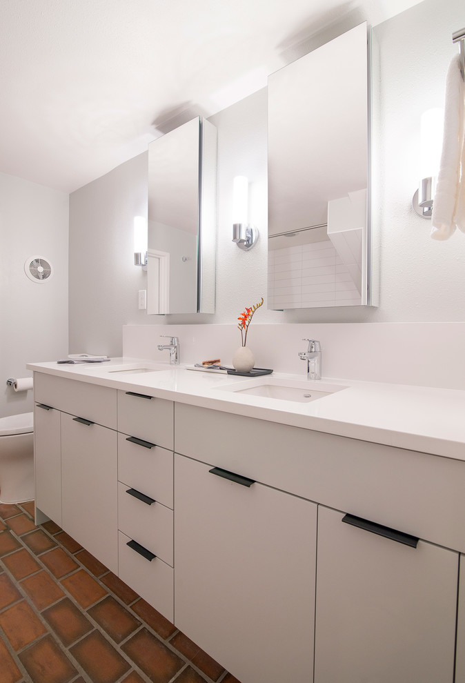 На фото: ванная комната среднего размера в стиле модернизм с плоскими фасадами, белыми фасадами, кирпичным полом и белой столешницей с