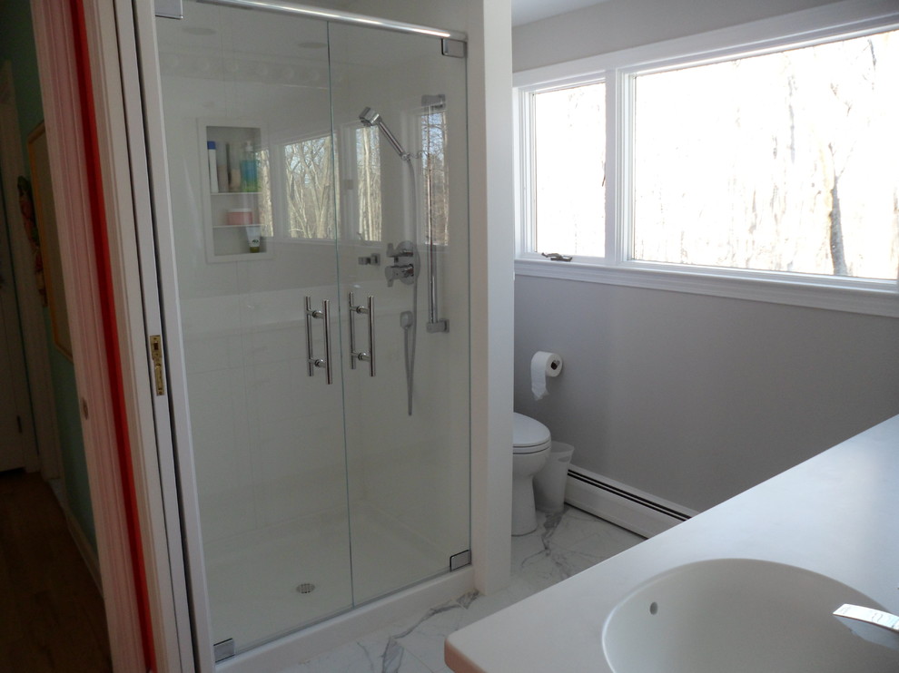 Inspiration for a small modern shower room bathroom in Bridgeport with flat-panel cabinets, white cabinets, solid surface worktops, grey tiles, stone tiles, an alcove shower, a one-piece toilet, an integrated sink, grey walls and marble flooring.