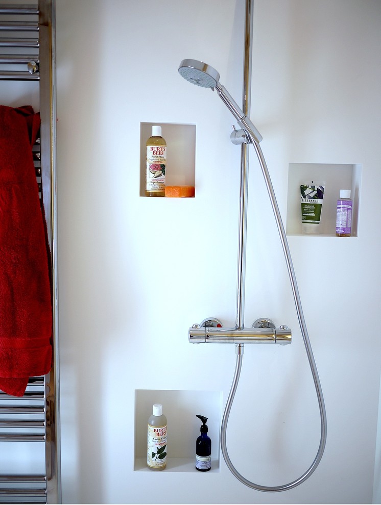Imagen de cuarto de baño principal contemporáneo pequeño con lavabo integrado, puertas de armario blancas, encimera de acrílico, ducha abierta, sanitario de pared y paredes blancas