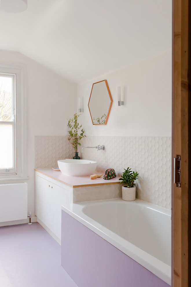Пример оригинального дизайна: ванная комната в современном стиле с плоскими фасадами, белыми фасадами, ванной в нише, белой плиткой, белыми стенами, настольной раковиной, фиолетовым полом и белой столешницей