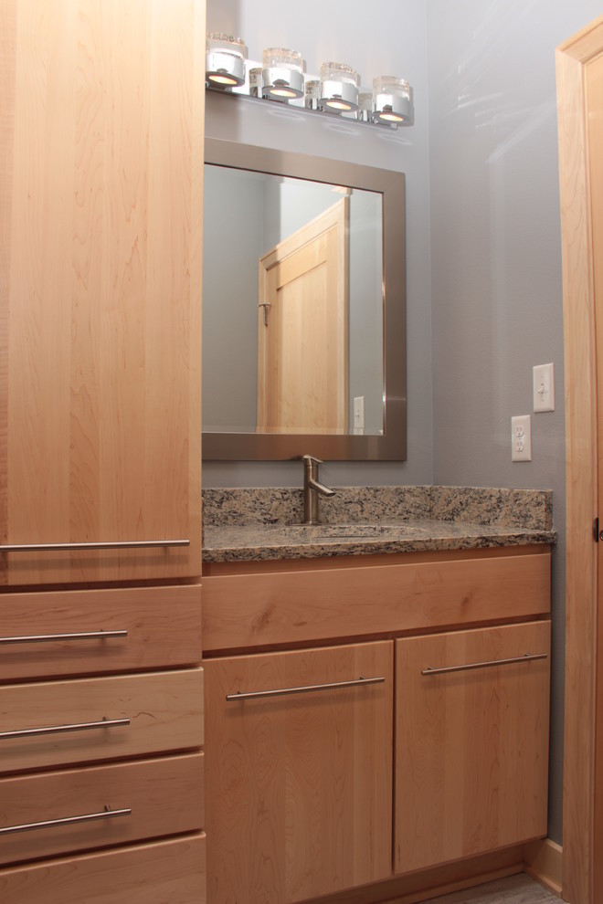 На фото: ванная комната в стиле модернизм с светлыми деревянными фасадами, серыми стенами, полом из керамогранита, врезной раковиной, столешницей из гранита, плоскими фасадами, серой плиткой и керамогранитной плиткой с