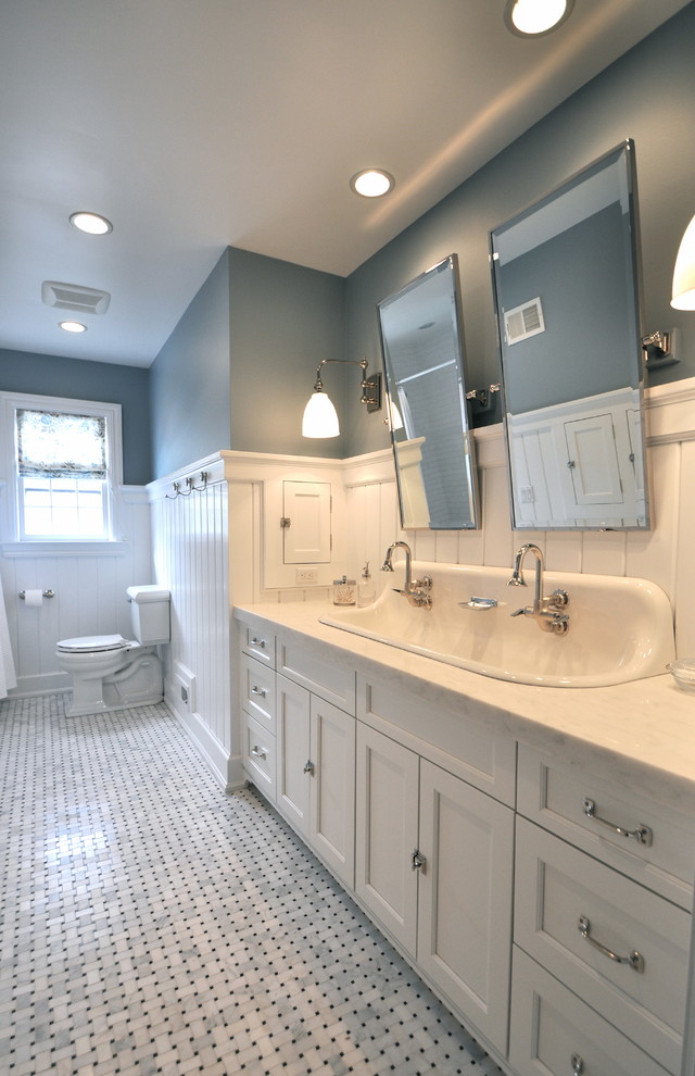Cette photo montre une salle de bain chic de taille moyenne pour enfant avec un placard à porte shaker, des portes de placard blanches, un plan de toilette en marbre, une baignoire en alcôve, WC séparés, un carrelage blanc, un carrelage métro, un mur bleu et un sol en marbre.