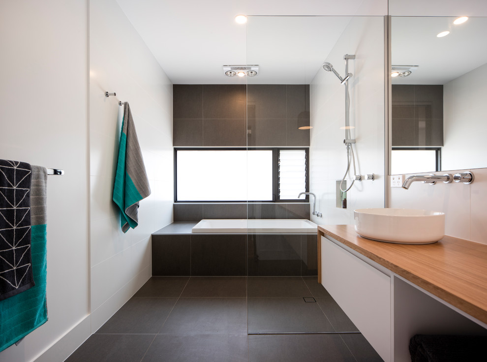 Bathroom - mid-sized contemporary kids' white tile and porcelain tile porcelain tile and gray floor bathroom idea in Sunshine Coast with furniture-like cabinets, white cabinets, a one-piece toilet, white walls, a vessel sink and wood countertops