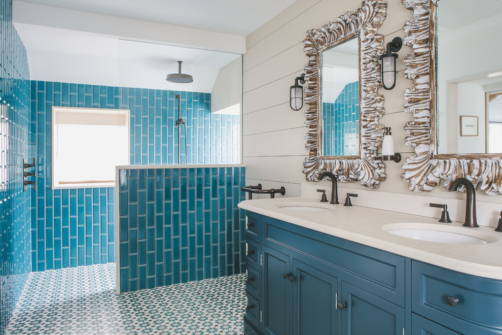 Cette image montre une salle de bain principale marine avec un placard avec porte à panneau encastré, des portes de placard turquoises, une douche ouverte, un carrelage bleu, un mur beige, un lavabo encastré, un sol multicolore, aucune cabine et un plan de toilette beige.