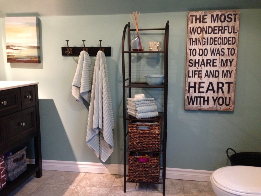 Modelo de cuarto de baño tradicional pequeño con armarios tipo mueble, puertas de armario de madera en tonos medios, sanitario de una pieza, paredes azules, suelo vinílico, lavabo integrado y encimera de acrílico