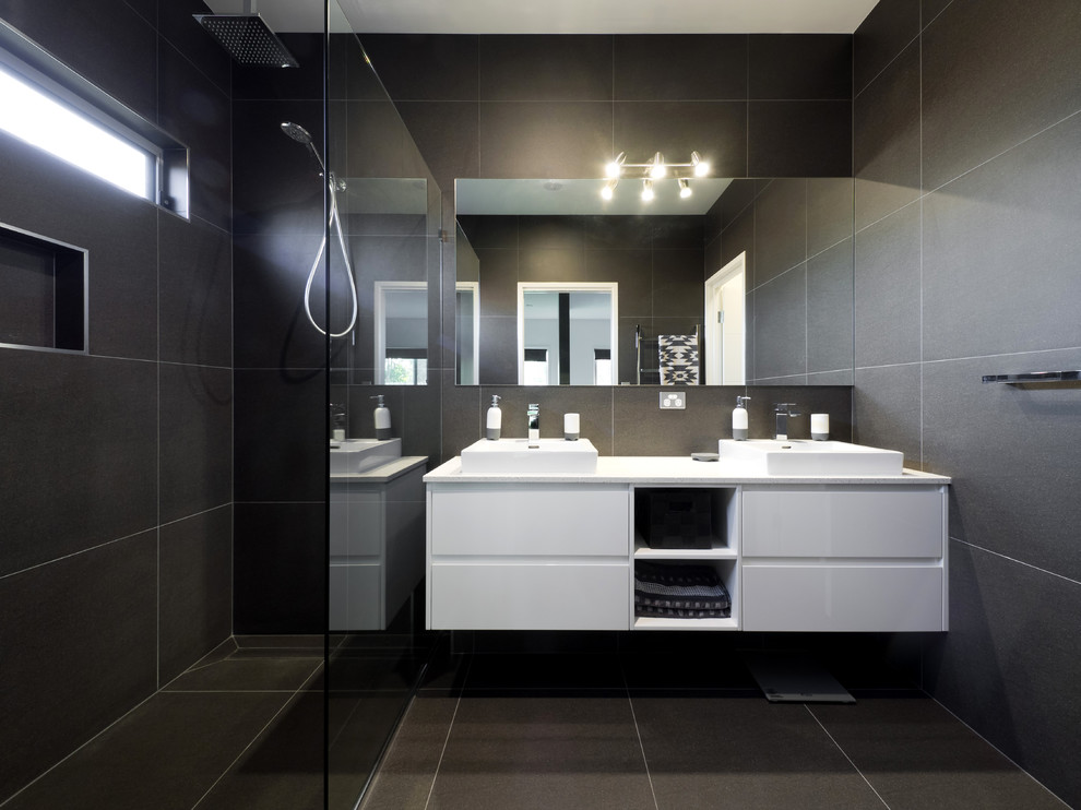 Cette image montre une salle d'eau design avec un placard à porte plane, des portes de placard blanches, une douche à l'italienne, un carrelage noir et une vasque.