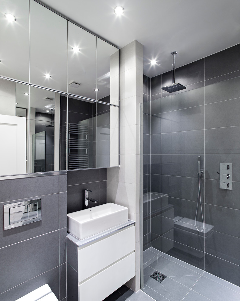 ロンドンにあるコンテンポラリースタイルのおしゃれな浴室 (ベッセル式洗面器、フラットパネル扉のキャビネット、白いキャビネット、アルコーブ型シャワー、グレーのタイル) の写真