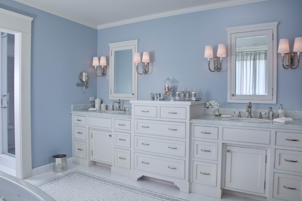 Modelo de cuarto de baño principal costero con armarios estilo shaker, puertas de armario blancas, paredes azules, suelo con mosaicos de baldosas, lavabo bajoencimera y encimera de mármol