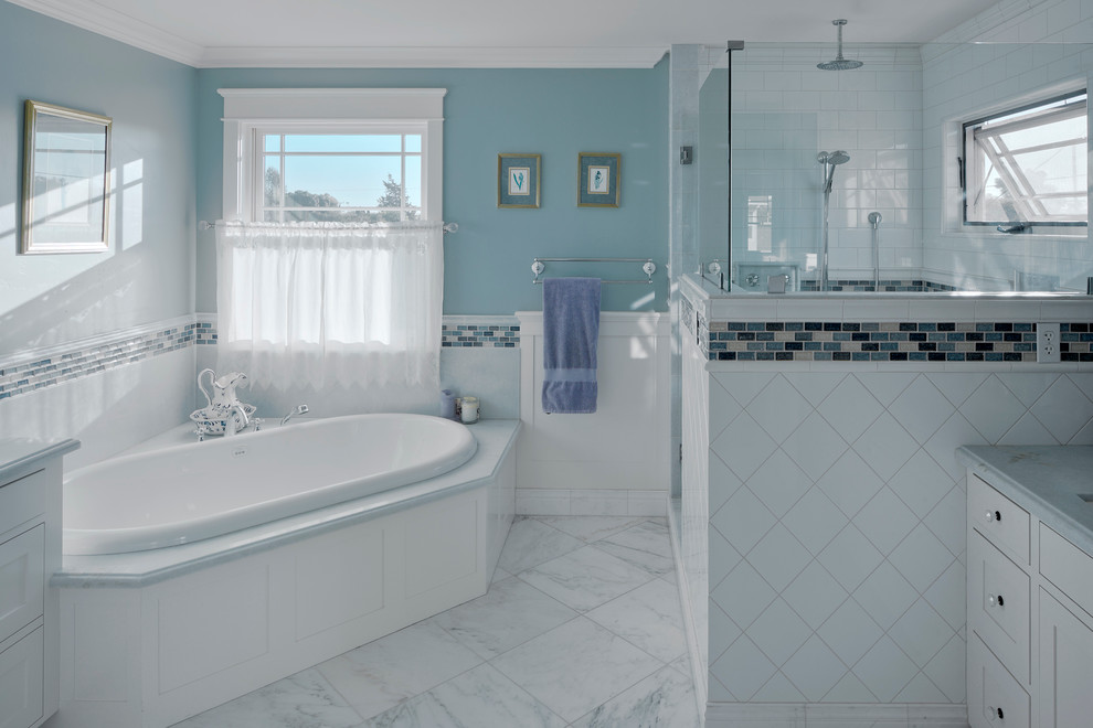 Idée de décoration pour une salle de bain principale tradition de taille moyenne avec un placard à porte shaker, des portes de placard blanches, un plan de toilette en marbre, une baignoire posée, une douche d'angle, un carrelage blanc, un carrelage métro, un mur bleu et un sol en marbre.