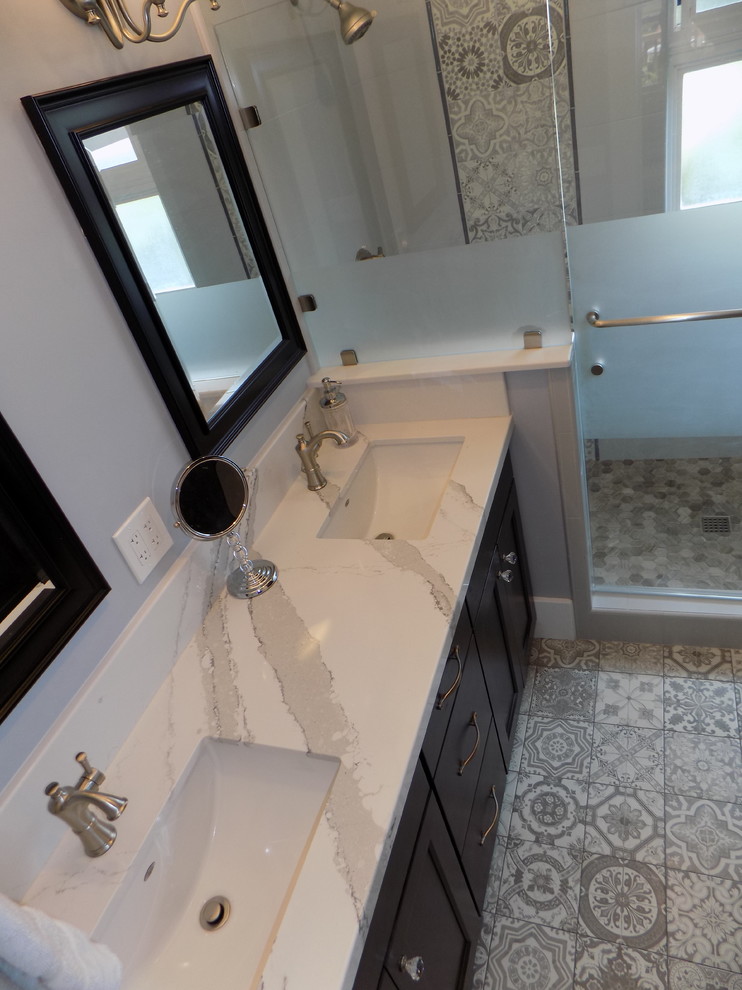 Cette photo montre une salle de bain romantique avec un placard à porte shaker, des portes de placard noires, une douche ouverte, WC à poser, un carrelage gris, des carreaux de porcelaine, un mur gris, un sol en carrelage de porcelaine, un lavabo encastré, un plan de toilette en quartz modifié, un sol gris et une cabine de douche à porte battante.