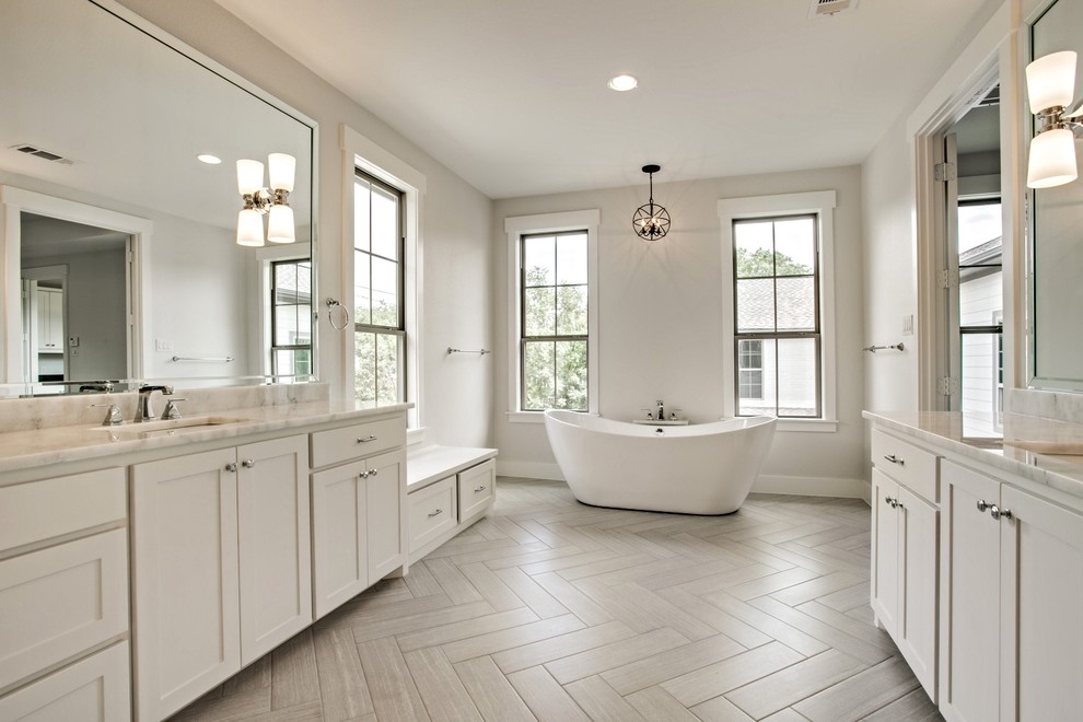 Idées déco pour une grande salle de bain principale classique avec un placard avec porte à panneau encastré, des portes de placard blanches, une baignoire indépendante, un mur gris, un sol en ardoise, un lavabo encastré, un plan de toilette en marbre et un sol gris.