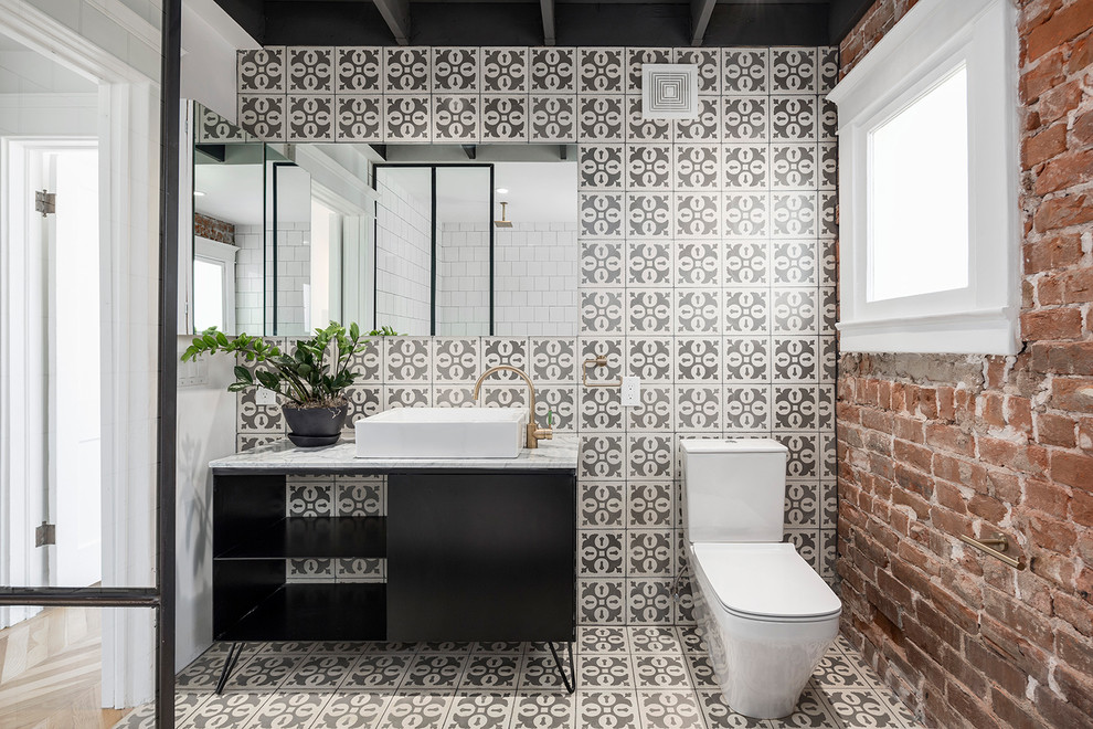 This is an example of an urban bathroom in Phoenix with a vessel sink, flat-panel cabinets, black cabinets, a two-piece toilet and multi-coloured tiles.