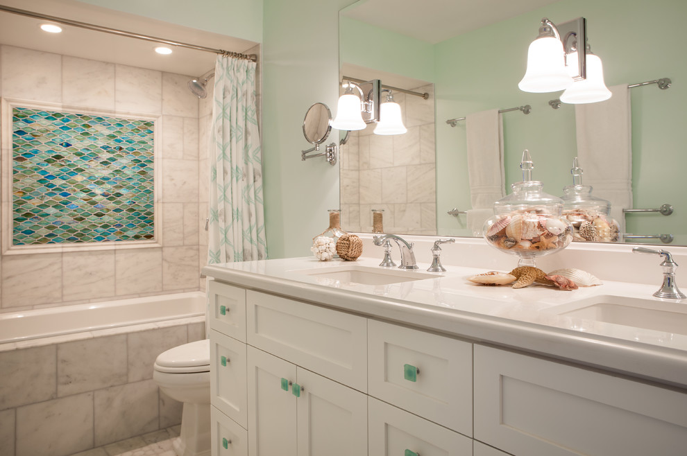 Cette image montre une petite salle de bain principale marine avec un placard à porte affleurante, des portes de placard blanches, une baignoire d'angle, un combiné douche/baignoire, WC à poser, un carrelage multicolore, mosaïque, un mur vert, un sol en carrelage de céramique, un lavabo encastré et un plan de toilette en surface solide.