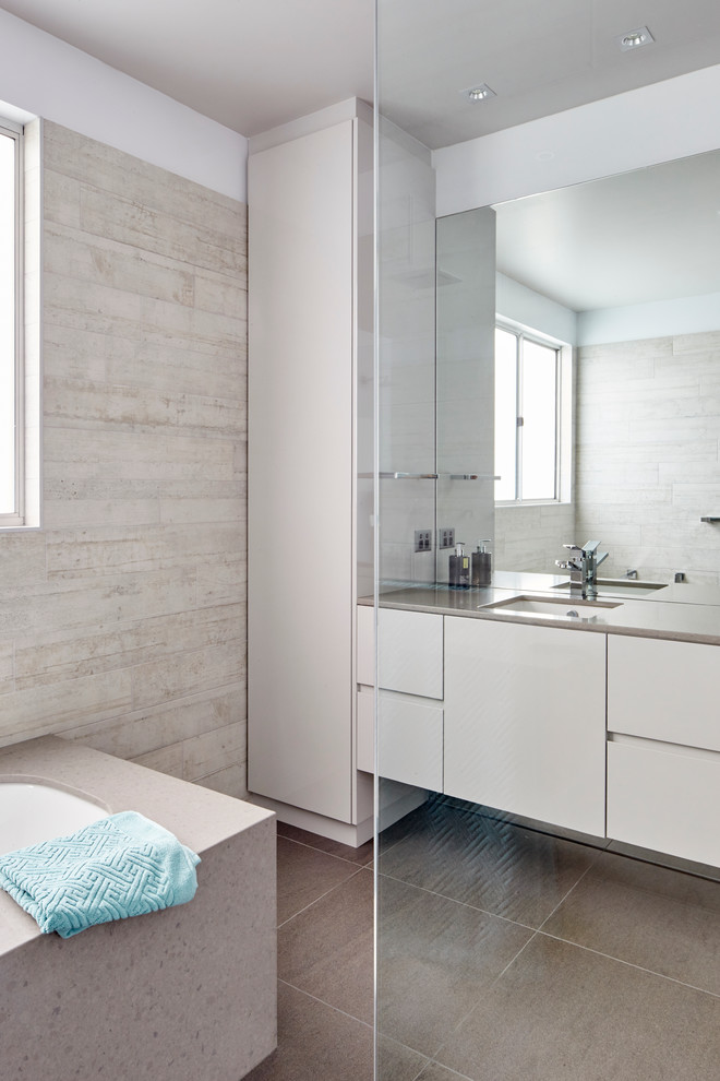 This is an example of a medium sized modern ensuite bathroom in Wollongong with grey cabinets, a submerged bath, a walk-in shower, a one-piece toilet, grey tiles, ceramic flooring and engineered stone worktops.
