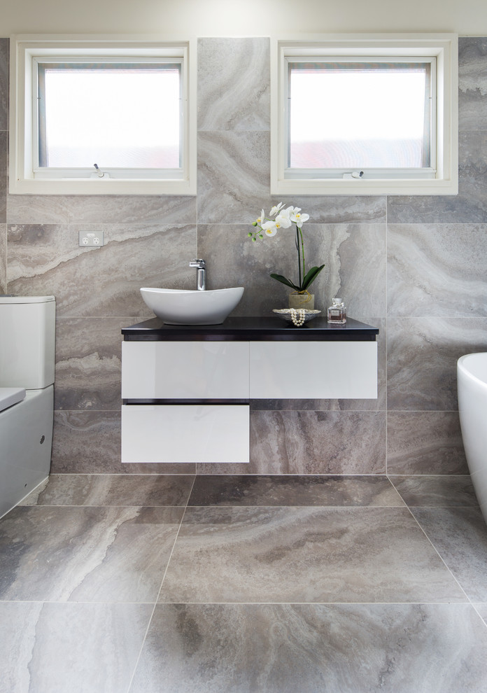 На фото: ванная комната среднего размера в современном стиле с серой плиткой, керамогранитной плиткой, душевой кабиной и столешницей из гранита с