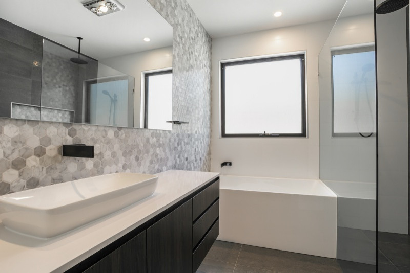 Mittelgroßes Modernes Badezimmer mit hellbraunen Holzschränken, grauen Fliesen, Keramikfliesen, Keramikboden, Quarzwerkstein-Waschtisch, grauem Boden und schwarzer Waschtischplatte in Brisbane