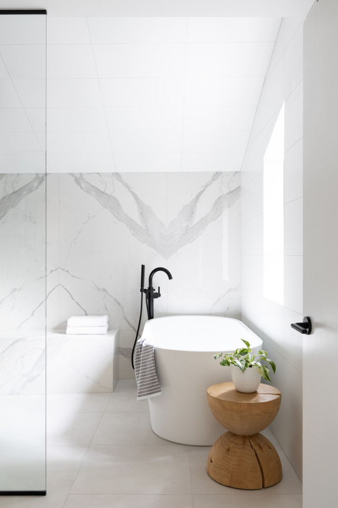 Cette image montre une salle de bain design avec une baignoire indépendante, un carrelage blanc et un sol blanc.