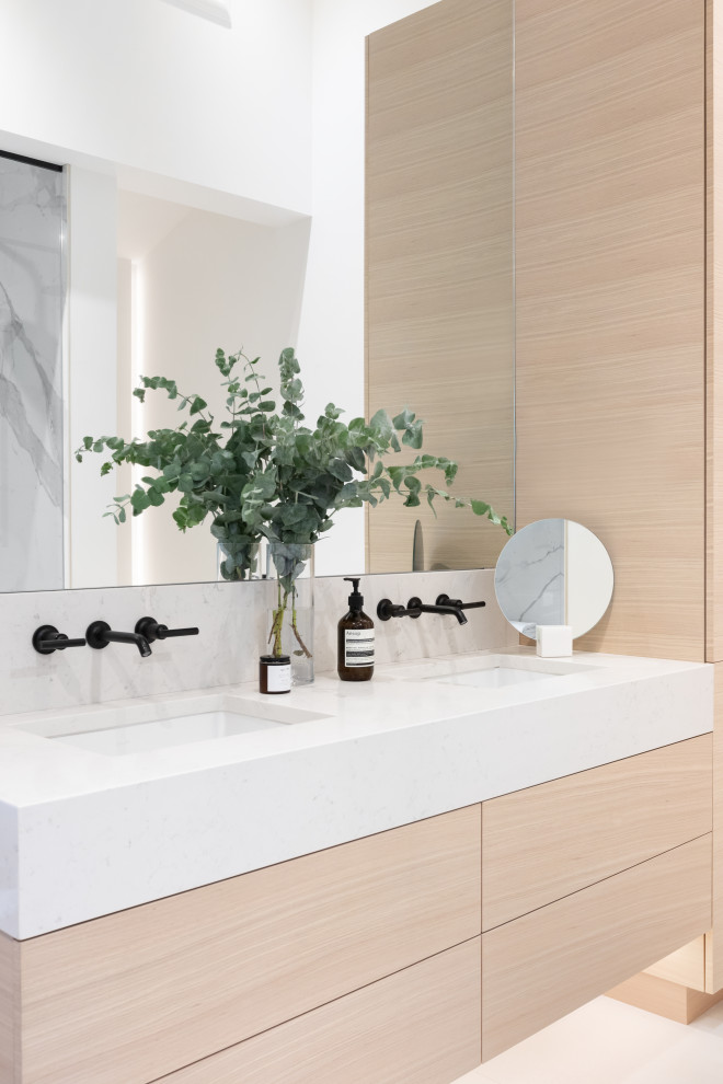 Immagine di una stanza da bagno minimal con ante lisce, ante in legno chiaro, lavabo sottopiano, pavimento bianco, top bianco e due lavabi