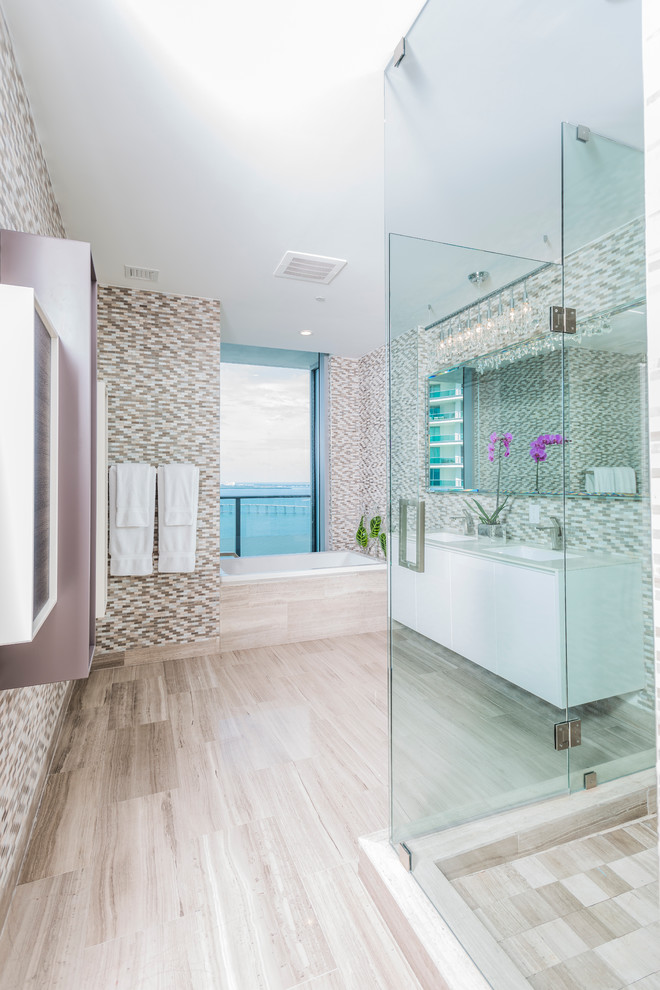 На фото: большая главная ванная комната в современном стиле с плоскими фасадами, белыми фасадами, угловой ванной, открытым душем, унитазом-моноблоком, разноцветной плиткой, удлиненной плиткой, бежевыми стенами, светлым паркетным полом, накладной раковиной, столешницей из искусственного камня, бежевым полом и открытым душем