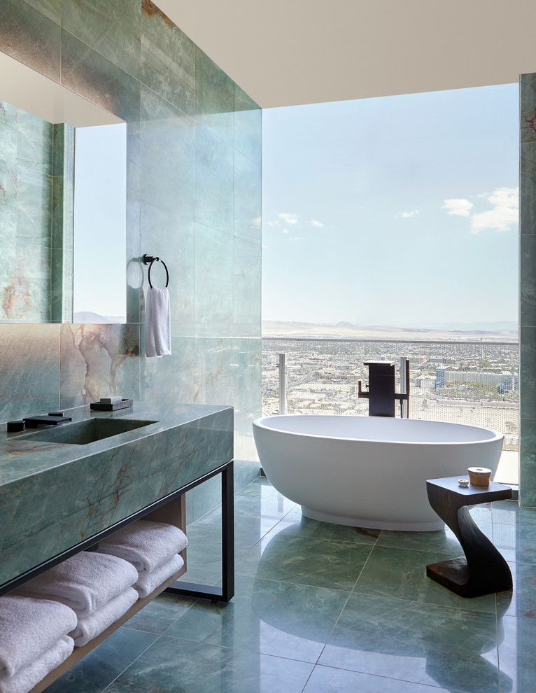Modern inredning av ett grön grönt badrum, med ett fristående badkar, grön kakel, marmorkakel, gröna väggar, marmorgolv, ett integrerad handfat, marmorbänkskiva och grönt golv