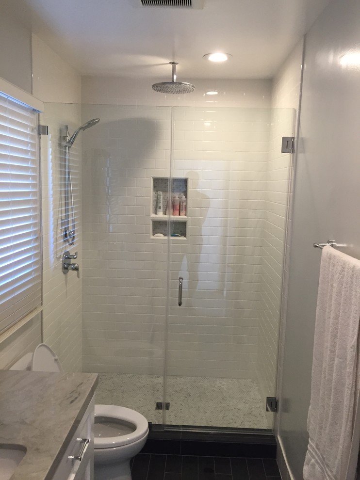 Inspiration for a small traditional shower room bathroom in Orange County with shaker cabinets, white cabinets, an alcove shower, a one-piece toilet, white tiles, ceramic tiles, white walls, porcelain flooring, a submerged sink, quartz worktops, black floors, a hinged door and grey worktops.