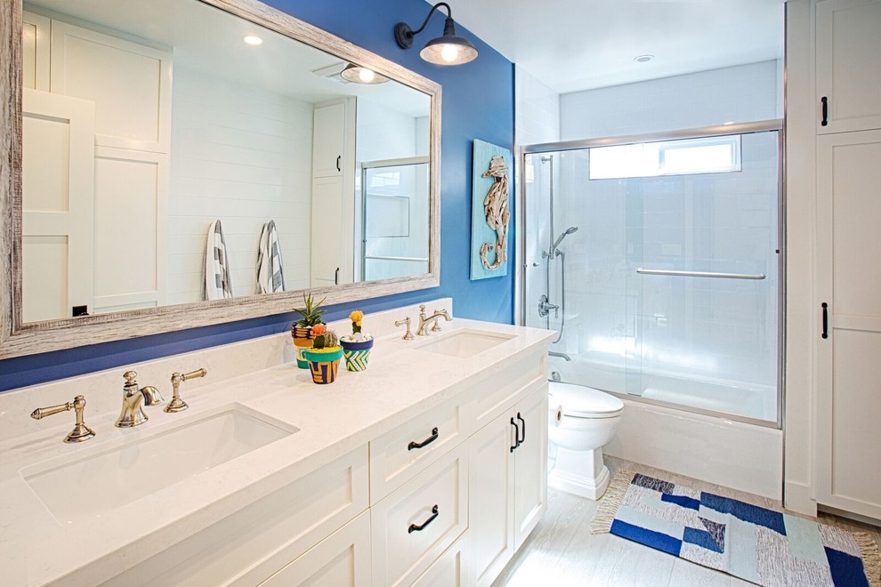 Idéer för stora funkis en-suite badrum, med skåp i shakerstil, vita skåp, ett badkar i en alkov, en dusch/badkar-kombination, en toalettstol med separat cisternkåpa, vit kakel, keramikplattor, blå väggar, klinkergolv i porslin, ett nedsänkt handfat, laminatbänkskiva, vitt golv och dusch med skjutdörr