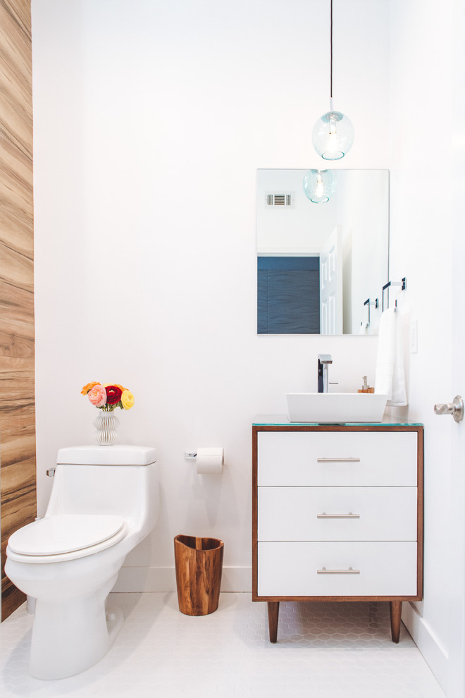 Inredning av ett modernt litet badrum med dusch, med vita väggar, ett fristående handfat, bänkskiva i glas, vitt golv, skåp i mellenmörkt trä, ett badkar i en alkov, en dusch/badkar-kombination, en toalettstol med hel cisternkåpa, klinkergolv i keramik, dusch med skjutdörr och släta luckor