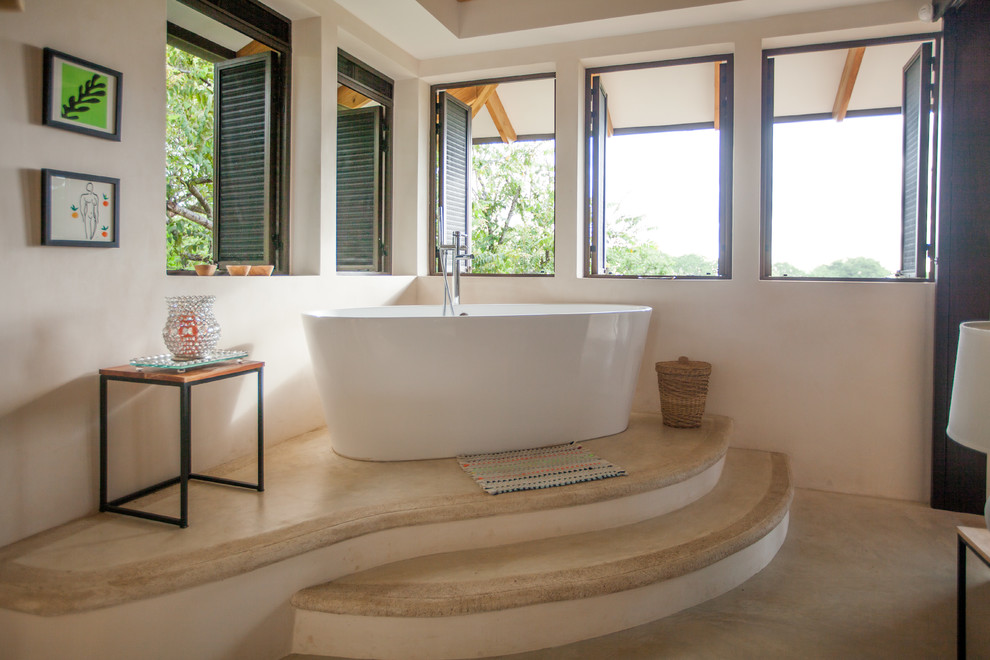 Foto di una stanza da bagno tropicale con vasca freestanding e pavimento beige