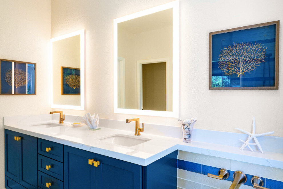 Idée de décoration pour une petite douche en alcôve principale marine avec un placard à porte shaker, des portes de placard bleues, une baignoire encastrée, WC à poser, un carrelage bleu, un carrelage en pâte de verre, un mur beige, un sol en carrelage de porcelaine, un lavabo encastré, un plan de toilette en quartz modifié, un sol beige, une cabine de douche à porte battante, un plan de toilette blanc, une niche, meuble double vasque et meuble-lavabo sur pied.