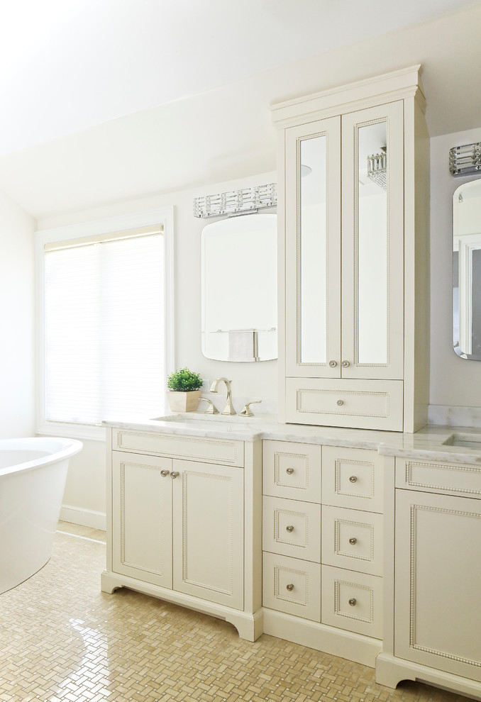 Idee per una stanza da bagno classica di medie dimensioni con ante beige, piastrelle beige, piastrelle di marmo, top in marmo, ante con riquadro incassato, vasca freestanding, pavimento con piastrelle a mosaico, lavabo sottopiano, pavimento beige e top bianco