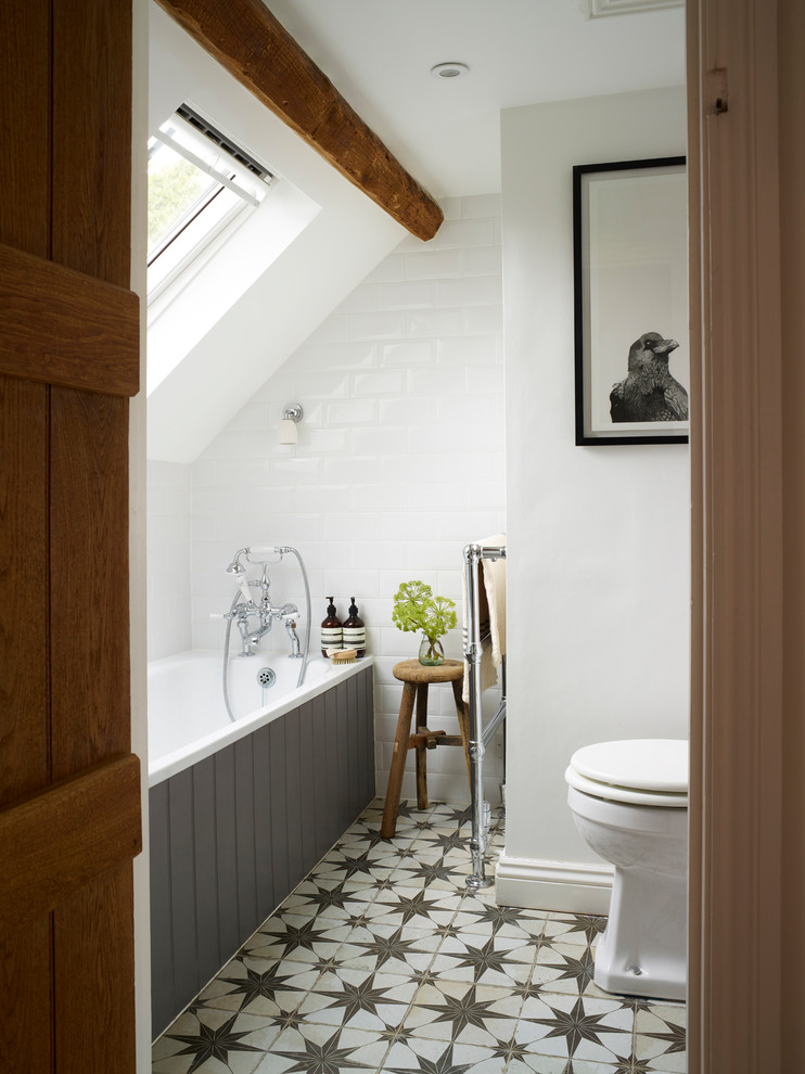 Small rural ensuite bathroom in Oxfordshire with a built-in bath, a two-piece toilet, white tiles, white walls and porcelain flooring.