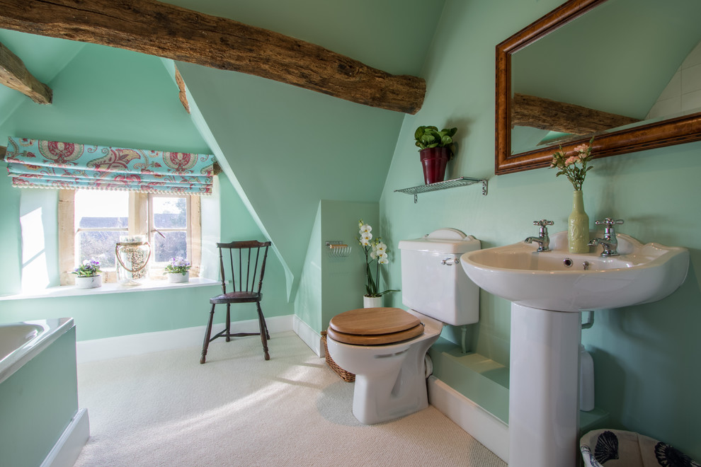 Großes Landhaus Badezimmer mit grüner Wandfarbe, Einbaubadewanne, Wandtoilette mit Spülkasten und Sockelwaschbecken in Gloucestershire
