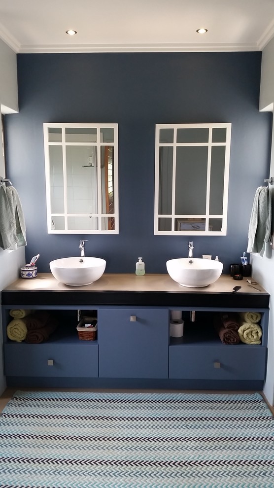 Cette image montre une petite salle de bain design avec un placard à porte plane, des portes de placard bleues et un mur bleu.